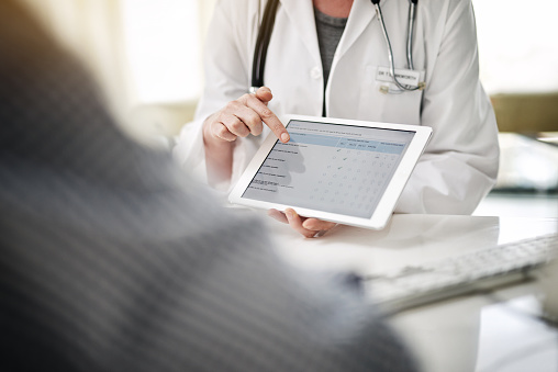Shot of oral surgeon showing patient online forms on a digital tablet at Virginia Surgical Arts in Virginia Beach, VA. Shot of oral surgeon showing patient online forms on a digital tablet at Virginia Surgical Arts in Virginia Beach, VA.