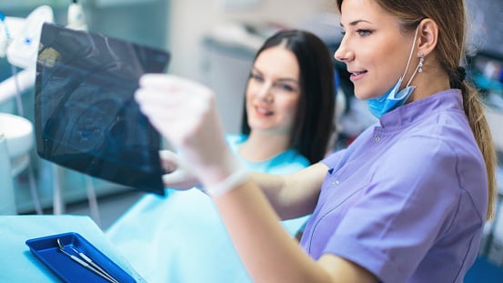 Dental assistant showing x-ray during dental implant consultation at Virginia Surgical Arts in Virginia Beach, VA