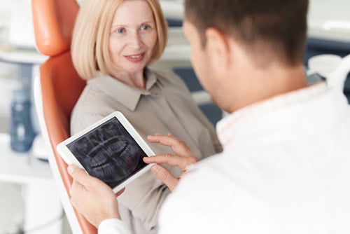 Older woman in dental chair with oral surgeon and X-ray at Virginia Surgical Arts in Virginia Beach, VA.