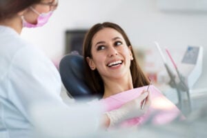 Young woman smiling and listening to oral surgeon during dental implant consultation at Virginia Surgical Arts in Virginia Beach, VA.