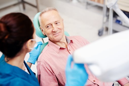 Senior man looking at his oral surgeon and listening to her advice after oral check-up at Virginia Surgical Arts in Virginia Beach, VA